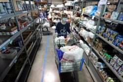 Worker Laura Burbank pushes a cart filled with food for a family through the pantry at GraceWorks Ministries food pantry in Franklin, Tenn, April 9, 2020.