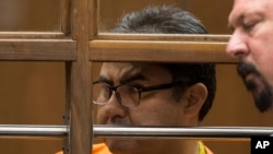 FILE - Naason Joaquin Garcia, the leader of Mexican megachurch La Luz del Mundo, behind bars, listens to a court interpreter as he appears with his attorneys in Los Angeles County Superior Court, in Los Angeles, California, June 21, 2019.