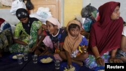 Migrants believed to be Rohingya take their breakfast inside a shelter after being rescued from boats at Lhoksukon, in Indonesia's Aceh Province, May 12, 2015.