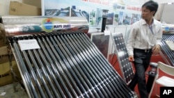 FILE - A solar water heater, left, and a solar panel are seen at Entech Hanoi, an international trade fair on energy efficiency and the environment, at the Giang Vo Exhibition Center in Hanoi, Vietnam.