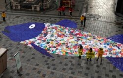 Some 800 shopping bags made of plastic sewed together in the shape of a fish are laid out by environmental activist group Greenpeace, in a protest against the pollution of oceans by plastic, in a street in Vienna.