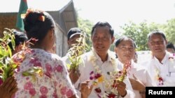 A woman presents flowers to former Myanmar ruling Union Solidarity and Development Party (USDP) chief Shwe Mann, as he campaigns at a village near his hometown Kanyuntkwin, Myanmar, Nov. 4, 2015. Myanmar will hold its historic general election on November