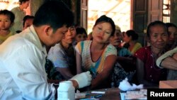 FILE - A government health worker takes a blood sample from a woman to be tested for malaria in Ta Gay Laung village hall in Hpa-An district in Kayin state, southeastern Myanmar, Nov. 28, 2014.