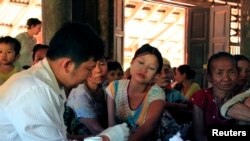 A government health worker takes a blood sample from a woman to be tested for malaria in Ta Gay Laung village hall in Hpa-An district in Kayin state, southeastern Myanmar, Nov. 28, 2014.
