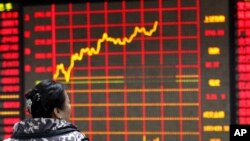 Seorang investor tengah mengamati papan elektronik yang menampilkan informasi saham di sebuah perusahaan sekuritas di Huaibei, provinsi Anhui (29/1).