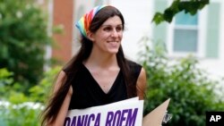 FILE - Danica Roem, then the Democratic nominee for the House of Delegates' 13th District seat, holds campaign signs as she canvasses a neighborhood in Manassas, Virginia, June 21, 2017. Roem became the nation's first openly transgender woman elected to a state legislature when she defeated Delegate Robert Marshall Nov. 7.