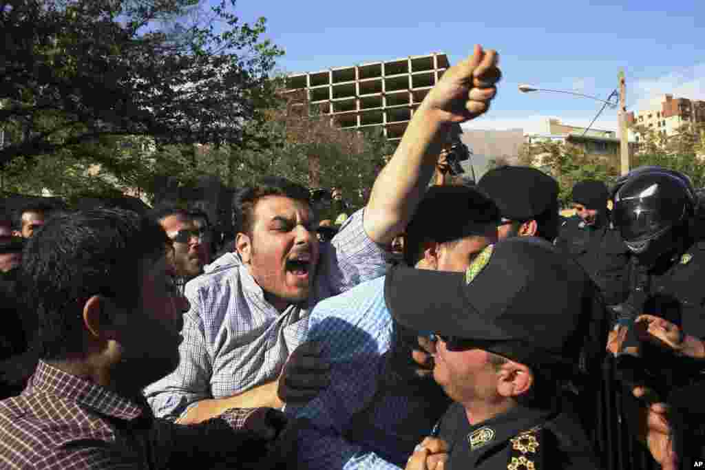 An Iranian protester chants slogans while police officers prevent him from getting near the embassy of Saudi Arabia in Tehran, Sept. 27, 2015.
