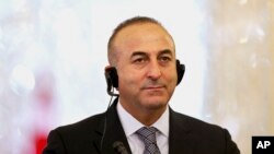 Menlu Turki Mevlut Cavusoglu mendengarkan terjemahan sebuah pertanyaan yang ditujukan kepadanya dalam sebuah konferensi pers (foto: dok). 