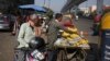 FILE - Jitendra Prasad takes money for bananas sold to an autorickshaw driver near Azadpur Mandi, Asia's largest wholesale market for fruits and vegetables in New Delhi, India, Nov. 22, 2016. India has slightly trimmed its economic outlook for 2016.