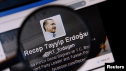 An image of Turkish Prime Minister Tayyip Erdogan on a Twitter account is pictured through a magnifying glass in this illustration picture taken in Istanbul March 21, 2014.