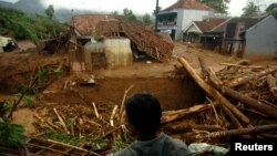 A villager stands near damaged houses after a landslide hit Pasir Panjang village in Brebes, Indonesia, Feb. 23, 2018. Antara Foto/Oky Lukmansyah/ via Reuters