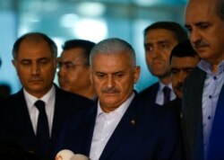 Turkey's Prime Minister Binali Yildirim, center, speaks to reporters next to Interior Miinister Efkan Ala, left, at the Ataturk airport in Istanbul, Turkey, following a multiple suicide bombing, June 29, 2016.