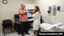 In this July 9, 2019 photo, Dr. Jori Fleisher, neurologist, examines Thomas Doyle, 66, at the Rush University Medical Center in Chicago. Doyle, 66, hopes blood tests may someday replace the invasive diagnostic testing he endured to be diagnosed 4.5 years 