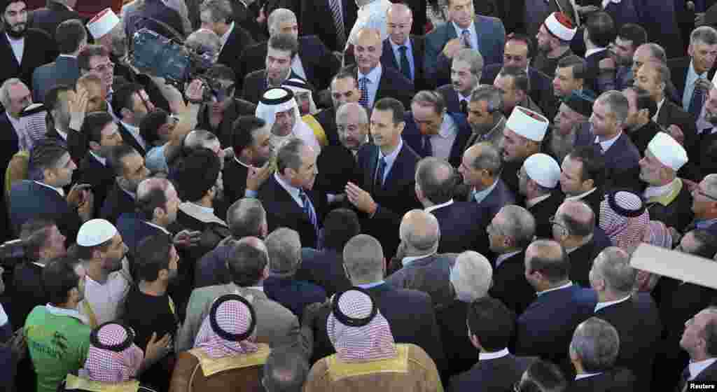 Syria's President Bashar al-Assad speaks with people after attending Eid al-Fitr prayers at Anas bin Malek mosque in Damascus, August 8, 2013. (SANA)