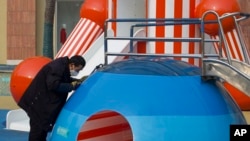 A cleaner carefully wipes down a playground at an empty mall district in Beijing, China, Feb. 12, 2020. 
