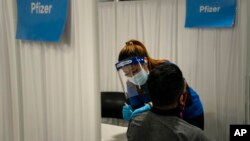 FILE - In this May 21, 2021, photo, licensed vocational nurse Angeline Gabuten administers the Pfizer COVID-19 vaccine to a patient at Providence Edwards Lifesciences vaccination site in Santa Ana, Calif. 