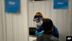 FILE - A nurse administers the Pfizer COVID-19 vaccine to a patient at Providence Edwards Lifesciences vaccination site in Santa Ana, California, May 21, 2021. 