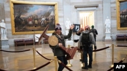 Seorang pengunjuk rasa pro-Trump membawa mimbar Ketua DPR AS Nancy Pelosi melalui Roturnda Gedung Capitol AS setelah massa pro-Trump menyerbu gedung pada 6 Januari 2021 di Washington, DC. (Foto: AFP)
