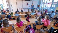 File picture taken Aug.3, 2020 shows teacher Francie Keller welcoming the pupils of class 3c in her classroom in the Lankow primary school to the first school day after the summer holidays in Schwerin, Germany, 2020