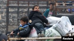 Anak-anak laki-laki duduk di atas tumpukan barang, menunggu evakuasi dari daerah pemberontak di Aleppo timur, Suriah (16/12). 