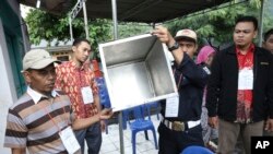 Electoral workers show an empty box before the opening station for voters during the gubernatorial election in Jakarta, Indonesia, Feb. 15, 2017.