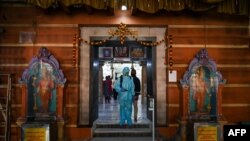 一名工作人员在孟买的一个印度教寺庙进行消毒，以避人们感染新冠病毒。图片：2020年11月15日