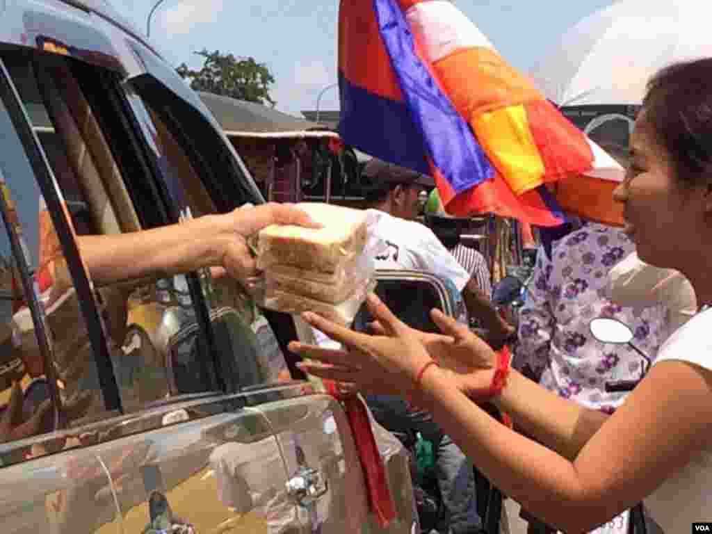 អ្នក​ចូលរួម​រំលែកទុក្ខ​​ចែក​អាហារ​ឲ្យ​ទៅ​អ្នក​ដទៃ​ទៀត​ ដែល​បាន​ចូលរួម​នៅ​ក្នុង​ពិធី​ដង្ហែ​សព​លោក​ កែម ឡី​ ទៅ​កាន់​ខេត្ត​តាកែវ នា​ថ្ងៃ​អាទិត្យ ទី​២៤ ខែ​កក្កដា ឆ្នាំ​២០១៦។ (ផន បុប្ឆា/VOA)