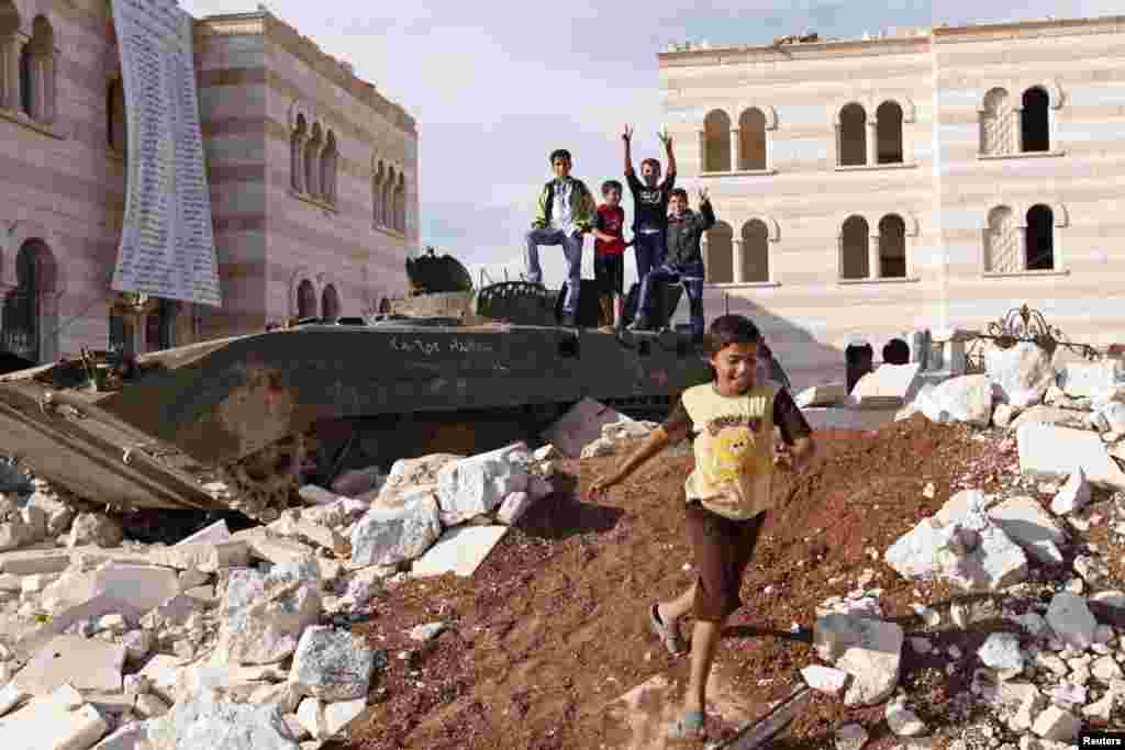 Children play on a destroyed armored personnel carrier belonging to forces loyal to Syria's President Bashar al-Assad in Azaz, in northern Syria near the border with Turkey, October 8, 2012. 
