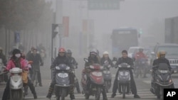 Chinese motorists ride their electric bikes in heavy fog down a street in Hefei, east China's Anhui province, 25 Nov 2009