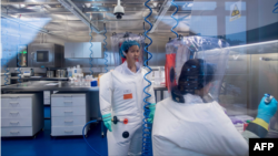 资料照：武汉病毒研究所的病毒学家石正丽（左）在该所的P4实验室内。