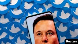 FILE PHOTO: Illustration shows Elon Musk image on smartphone and printed Twitter logos