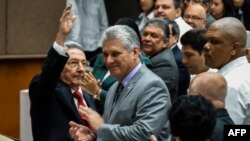 Le président cubain sortant, Raul Castro, à gauche, une main levée, aux côtés du président élu Miguel Diaz-Canel, lors d'une session de l'Assemblée nationale, à La Havane le 18 avril 2018.