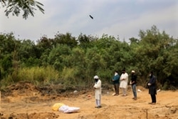 Relatives offer prayers before the burial of a Muslim woman who died of COVID-19 at a cemetery in New Delhi, India, Thursday, April 16, 2020.