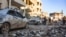 People check damage in a street following an airstrike by Syrian government forces in the town Maarrat Misrin, in Syria’s northwestern Idlib province, Feb. 25, 2020. 