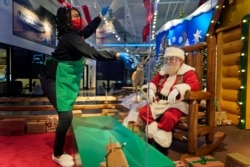 LaToya Booker cleans a transparent barrier between visitors for Santa at a Bass Pro Shop in Bridgeport, Conn., Nov. 10, 2020.
