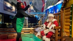 LaToya Booker cleans a transparent barrier between visitors for Santa at a Bass Pro Shop in Bridgeport, Conn., Nov. 10, 2020.