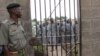 A corrections officer looks on as inmates gather near housing units at Naivasha Maximum Prison in Kenya, October 2014. (Gabe Joselow / VOA) 