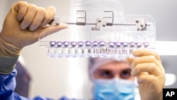 FILE - A technician inspects filled vials of the Pfizer-BioNTech COVID-19 vaccine at the company's facility in Puurs, Belgium, in this March 2021 photo provided by Pfizer.