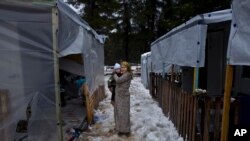 Shireen Daoud, 25 and three months pregnant, a Syrian refugee from al-Hasaka, holds her son Herman, 2, while posing for a picture by the entrance of her shelter, during snowfall at the refugee camp of Ritsona, Greece, Dec. 29, 2016. Squalid conditions and subfreezing temperatures in Greece’s migrant camps this winter are taking their toll on everyone living in them.