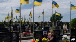 一位女士在乌克兰布查抚摸丈夫的墓碑，她的丈夫是乌克兰军人，在乌克兰顿涅茨克州阿夫卡迪伊夫卡阵亡。(2023年7月18日)