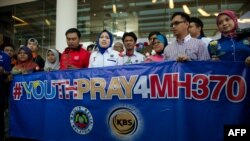 Members of a youth group holds roses and a banner as they pray for the missing Malaysia Airlines Boeing 777-200 plane at a hotel in Putrajaya on March 10, 2014. 