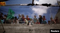 Anak-anak terlihat dari balik kain sedang menyaksikan pemakaman anak laki-laki Palestina, Majdi al-Satri, yang dibunuh tentara Israel dalam unjuk rasa di perbatasan Israel-Gaza, di Rafah, di selatan Jalur Gaza, 28 Juli 2018.