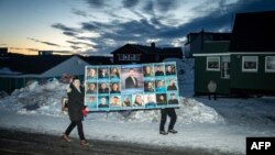 گیارہ مرچ کو الیکشن کے دن، دو افراد کامیاب ہونے والی پارٹی ڈیموکراٹٹ کے پوسٹر کے ساتھ۔ فوٹو اے ایف پی