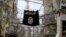 FILE - An Islamic State flag hangs amid electric wires, Jan. 19, 2016. 