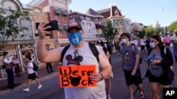 FILE - Visitors walk down Main Street USA at Disneyland in Anaheim, Calif. California, the first state in America to put in place a coronavirus lockdown, is now turning a page on the pandemic, April 30, 2021.