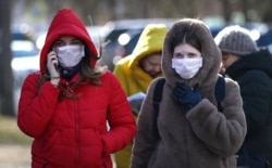 People wearing protective masks walk on street in Minsk, Belarus, Feb. 28, 2020. Azerbaijan, Belarus, Lithuania, New Zealand and Nigeria have reported their first cases of coronavirus.