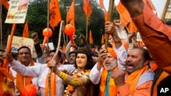 FILE - A man stands dressed as Hindu god Ram, center, as activists of right wing Hindu groups shout slogans demanding that a temple of Hindu god Ram be made at Ayodhya on the anniversary of the Babari Mosque demolition in New Delhi, India, Dec. 6, 2018. 