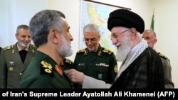 Iran's Supreme Leader Ayatollah Ali Khamenei (R) decorates, Oct. 6, 2024, the Islamic Revolutionary Guard Corps' Aerospace Force Commander Brigadier General Amir Ali Hajizadeh (L) with the 'Fath' badge in Tehran for planning the Iranian attack on Israel.