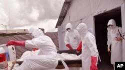 FILE - health workers wearing Ebola protective gear remove the body of a man they suspect died from the Ebola virus, at a USAID, American aid Ebola treatment center on the outskirts of Monrovia, Liberia, Nov. 28, 2014.
