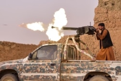 FILE - A member of an anti-Taliban militia fires a machine gun during a fight with Taliban insurgents in Mukhtar, on the outskirts of Lashkar Gah, Afghanistan, March 28, 2021.